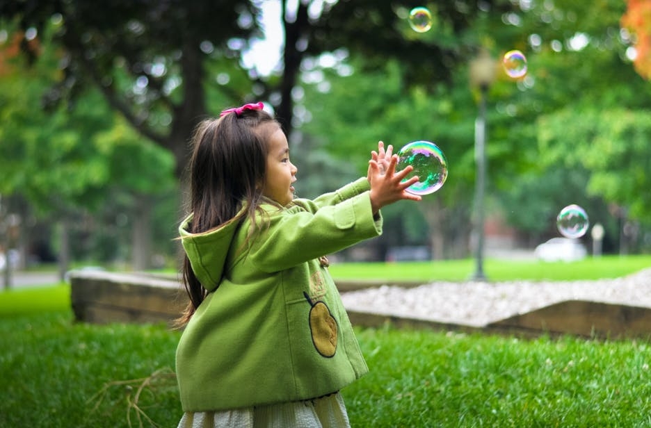 little girl playing with a bubble